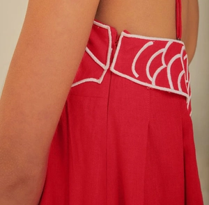Gros plan sur robe rouge en lin avec fermeture éclair invisible et broderie blanche en arc