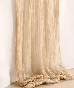 Close-up of beige wrinkled gauze cheesecloth fabric texture draped on wooden floor