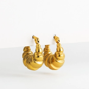 Macro detail of golden croissant style hollow hoop earrings with spiral texture