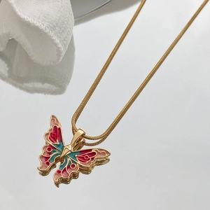 Elegant gold snake chain necklace featuring colorful enamel butterfly pendant on mirror