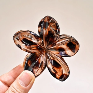 Detail of a floral hair claw clip featuring a classic tortoise shell pattern and metal spring