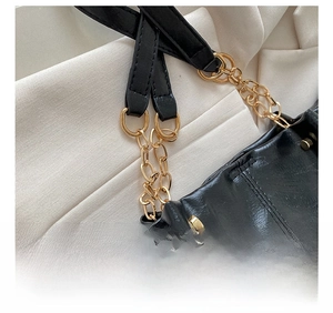 Détail de la bandoulière en cuir noir avec maillons de chaîne en métal doré chic