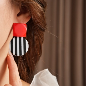 Close-up of geometric resin earrings with red square and black and white stripes on model