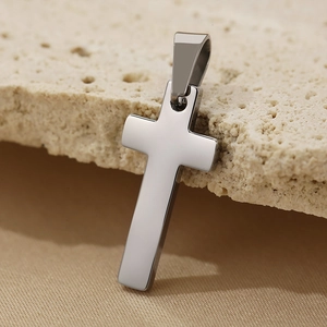 Detailed view of polished stainless steel cross pendant on textured stone background