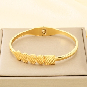 Detailed macro view of a gold-plated heart bracelet with textured heart motifs and spring clasp