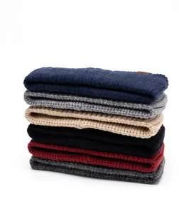 Detailed stack of ribbed knit beanies in navy, grey, beige, black, burgundy, and dark grey