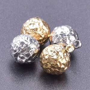 Close-up of hammered 18k gold and silver stainless steel charms with small hanging loops