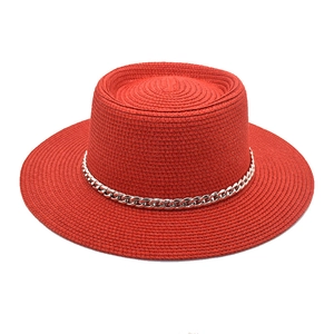 Detail of red boater straw hat featuring a stylish silver metal chain decoration