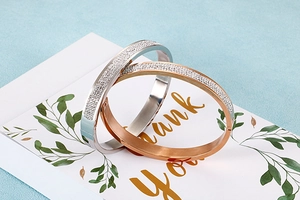 Détail de bracelets joncs en or rose et argent avec cristaux sur une carte cadeau