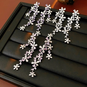 Detailed macro of silver tassel flower earrings with purple and pink zircon in a black tray