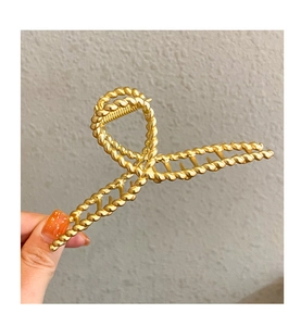 Detailed macro view of the twisted metal texture on the golden shark hair clip for women