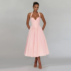Detailed shot of pink halter neck dress with bow waist and smooth satin-like fabric texture