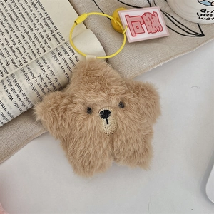 Detail of star-shaped brown plush bear keychain with cute embroidery on book pages