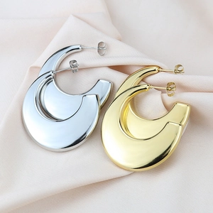 Detail of chunky gold and silver hollow hoop earrings on soft pink fabric
