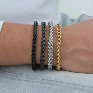 Detail of stacked keel chains in black, silver, and gold finishes on a male wrist