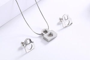 Detail of silver stainless steel jewelry set featuring hollow heart lock necklace and earrings