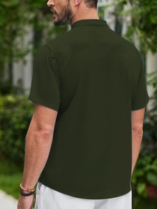 Rear view of man in dark green short sleeve polo shirt with textured fabric and collar