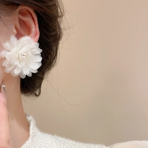 Close-up of elegant 3D white fabric flower earrings with pearls on model ear
