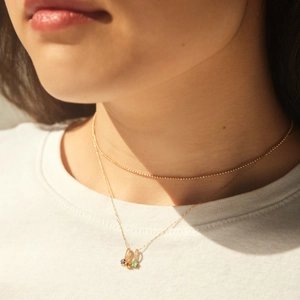 Detail of layered gold titanium steel necklaces with colorful birthstone pendant on a model