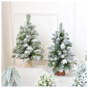 Group of various sized snowy mini Christmas trees with cedar wood base on a warm desk