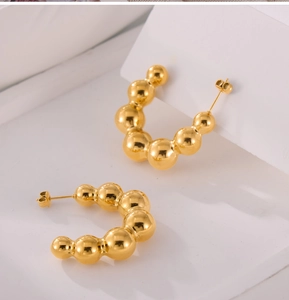 Macro view of minimalist 18K gold plated titanium steel beaded C-shaped stud earrings