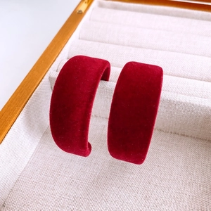 Gros plan de boucles d'oreilles en C floquées de velours bordeaux sur boîte à bijoux