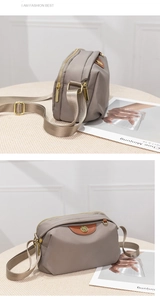 Detail view of mauve oxford fabric crossbody bag with gold zippers and multi-layer design