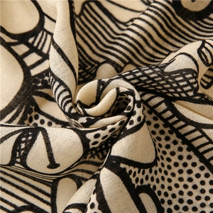 Close-up detail of beige cotton linen scarf with black abstract geometric patterns