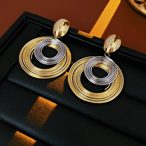 Macro detail of twisted spiral metal hoop earrings in gold and silver finish