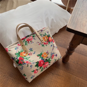 Close-up of vintage floral canvas tote bag featuring brown leather handles and rivets