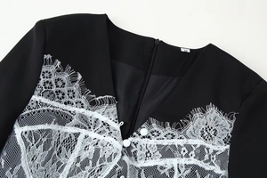 Détail du col en V avec tissu noir, dentelle blanche et étiquette de taille M