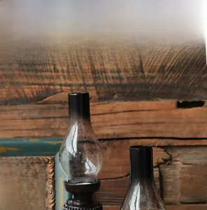 Dettaglio di lampada a petrolio in vetro e vaso in resina su sfondo in legno rustico