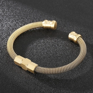 Détail d'un bracelet en maille dorée avec écrous hexagonaux et embouts cylindriques