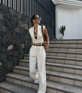 Detail of white sleeveless crop vest and wide-leg trousers set on a model outdoors