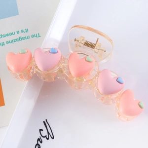 Detail of pink and orange heart hair claw clip on a white tray for a stylish look