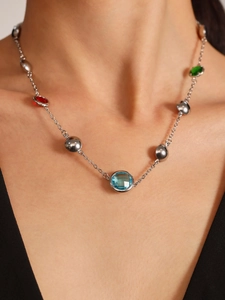Detail of silver chain necklace with multi-colored gemstones on female model