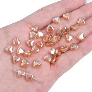 Macro shot of peach champagne glass heart beads held in hand for DIY jewelry making