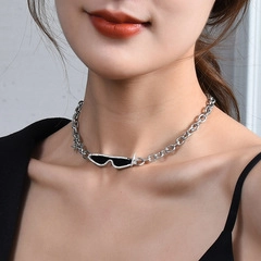Close-up of a silver punk-style chunky chain necklace with a black sunglasses pendant