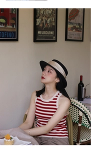 Detail of a French vintage flat top straw hat with black brim in a retro cafe setting