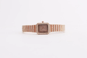 Macro shot of rose gold square watch dial and chain link band with crystal pavé details