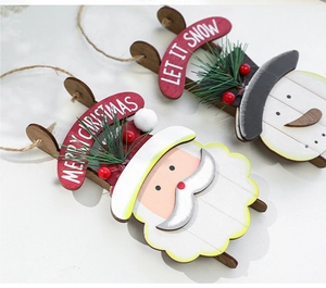 Detail of wooden Christmas sleigh ornaments with Merry Christmas text and pine needles