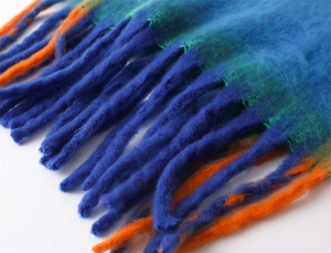 Detailed macro view of vibrant blue, green and orange gradient fringes on warm scarf