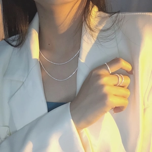 Double-layered sparkling silver necklace and matching rhinestone rings on a model