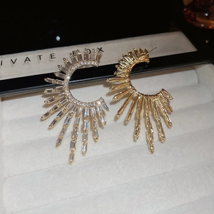 Macro shot of gold C-shaped earrings with sparkling square cubic zirconia on a velvet tray