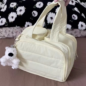Cream quilted handheld cosmetic bag with plush bear charm and dual zippers for travel