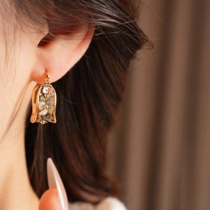 Macro detail of vintage gold-plated U-shaped earrings with inlaid rainbow shell fragments