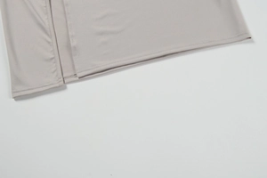 Detail view of the light grey dress showing double-needle hem stitching and side slit detail