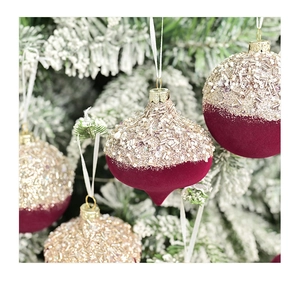 Detail of luxury flocked burgundy and gold sequin Christmas ornaments on snow pine