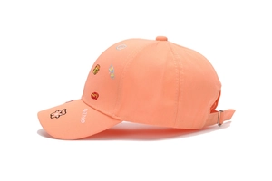 Detail of pink orange baseball cap featuring cartoon bear embroidery and DINO text