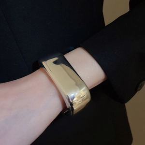 Close-up of polished silver wide wave cuff bracelet worn with a black suit jacket